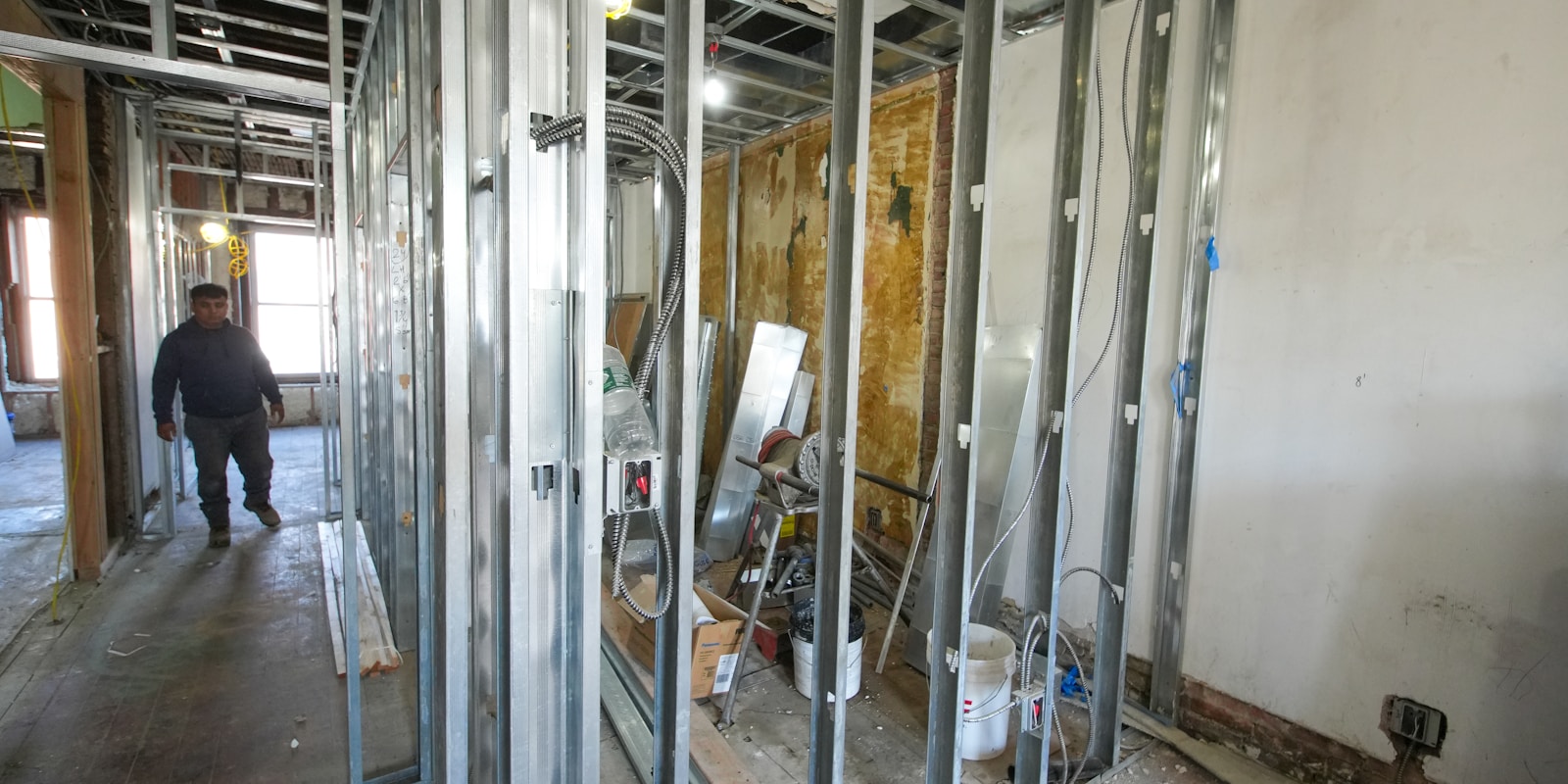 A man walks through a room featuring exposed metal framing and industrial design elements.