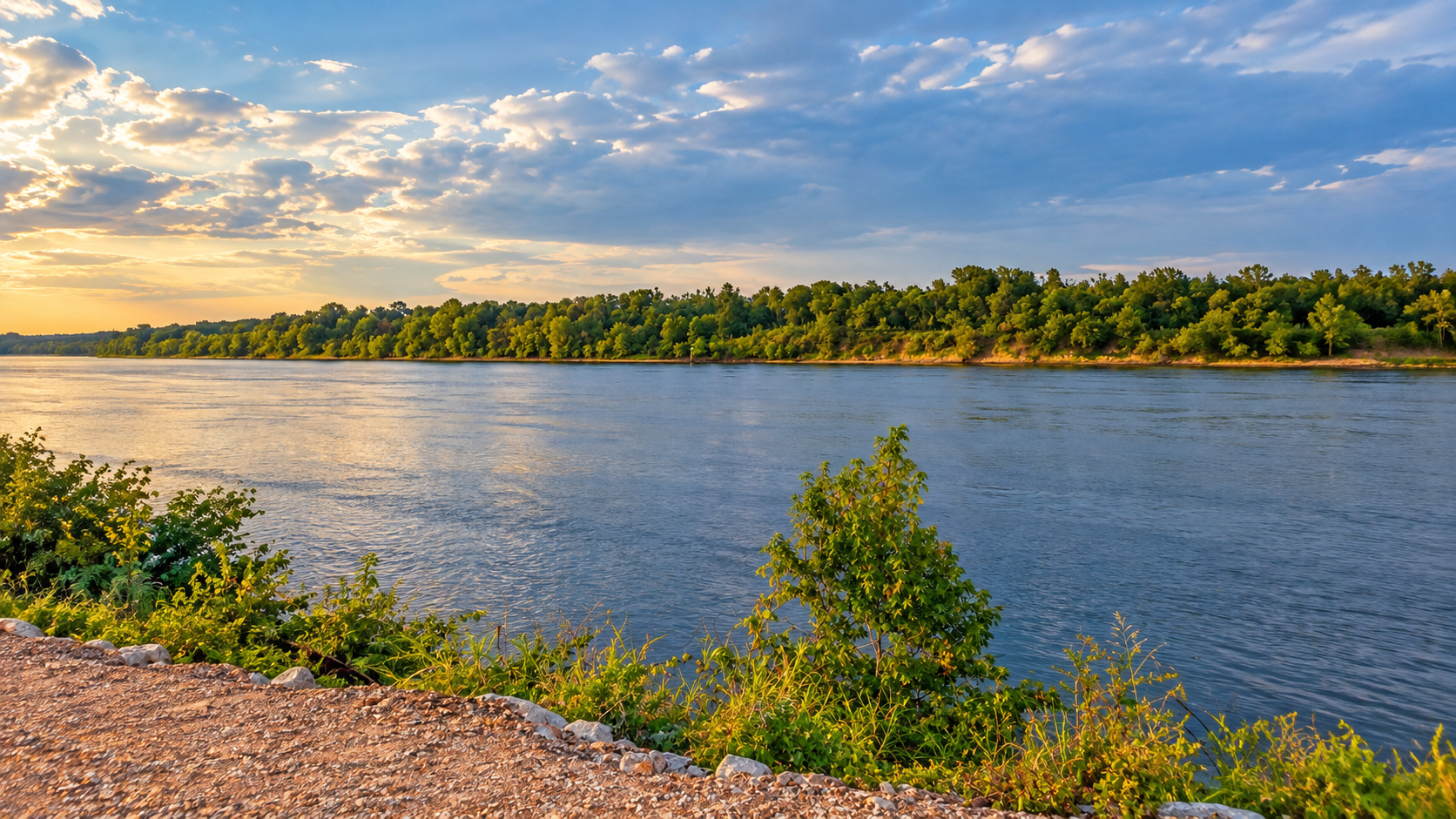 The Tennessee River winding past a wooded shoreline under a golden sunset near Shiloh