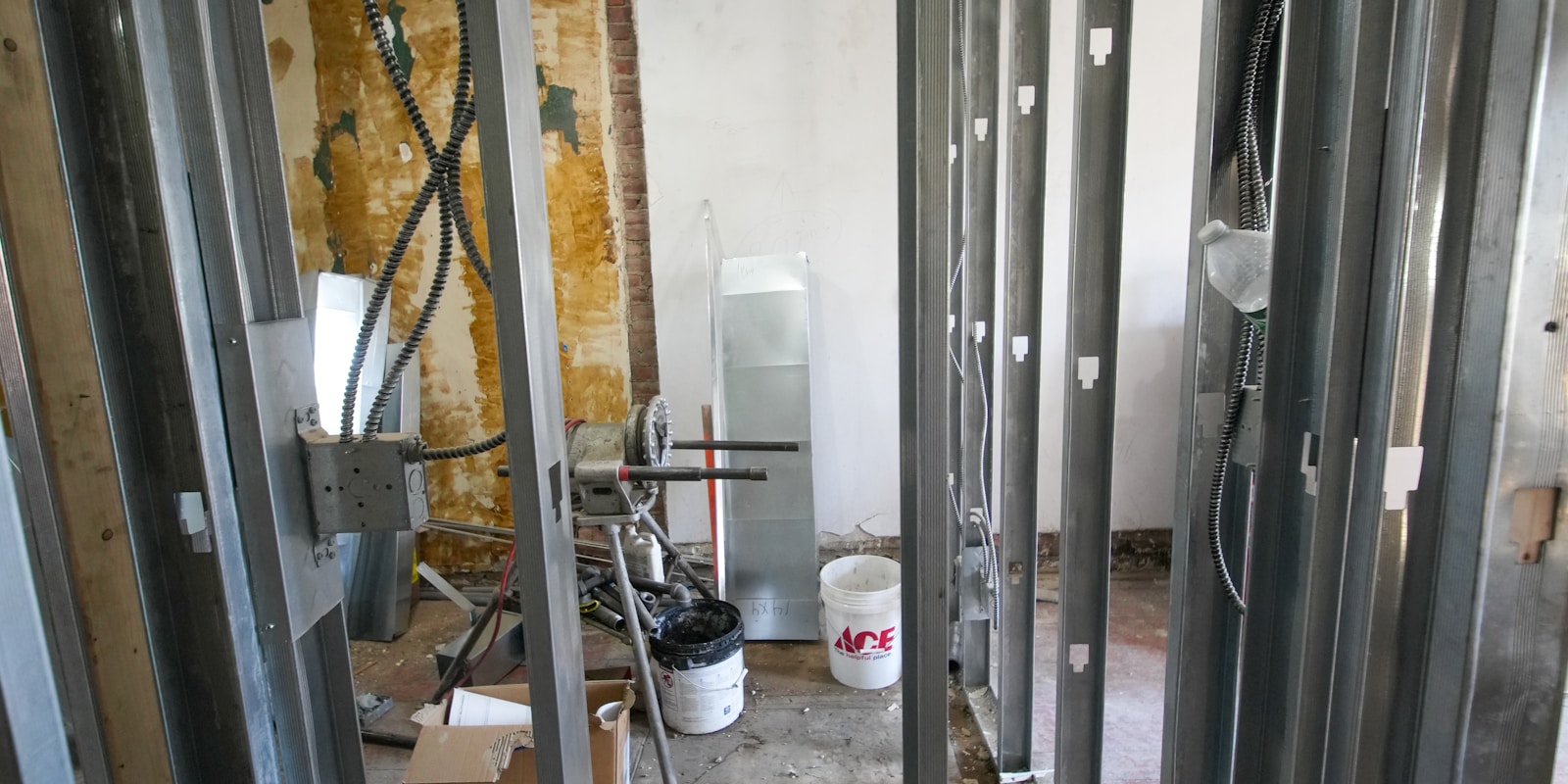 A room featuring exposed metal framing and plumbing pipes, showcasing an industrial design aesthetic.