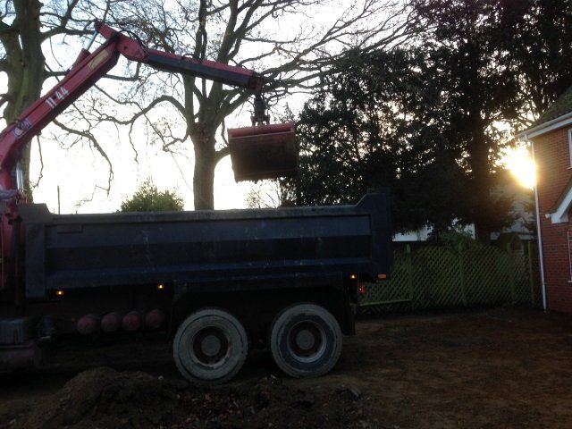 Grab lorry clearing spoil and delivering aggregates on a driveway project