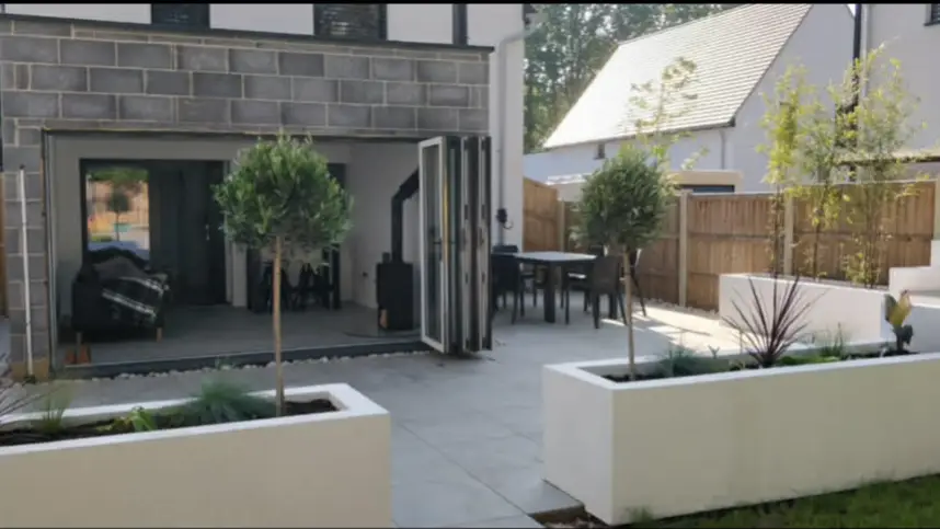 Sunlit landscaped garden with bench and lawn.