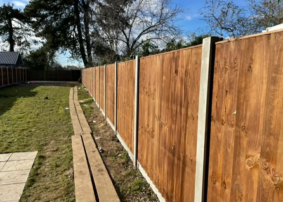 Garden fence meeting corner of a paved area.
