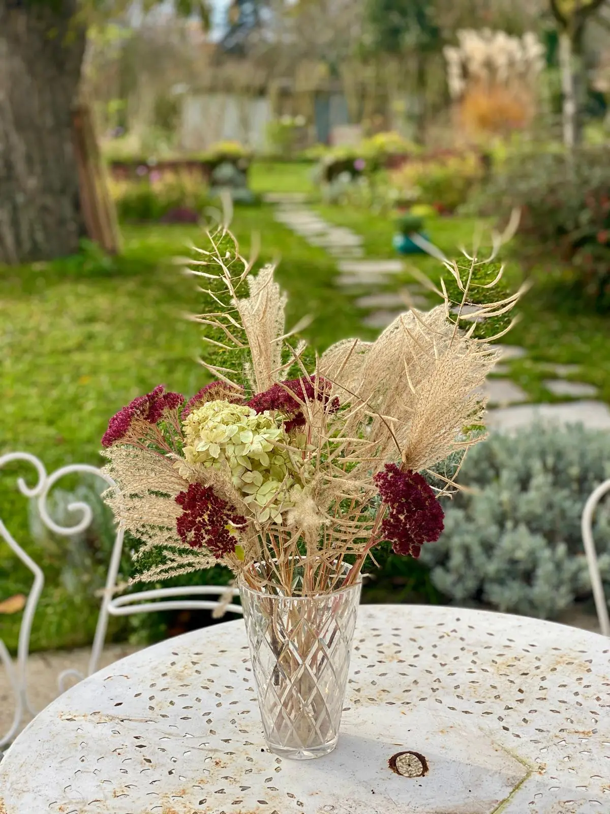 Dried autumn bouquet of hydrangea and grasses on a bistro table in the garden