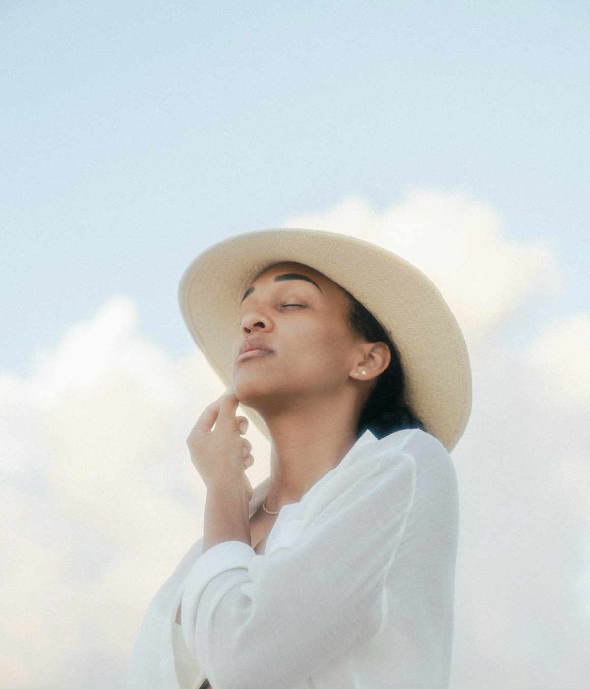 Frau in Bluse und Hut vor dem Himmel